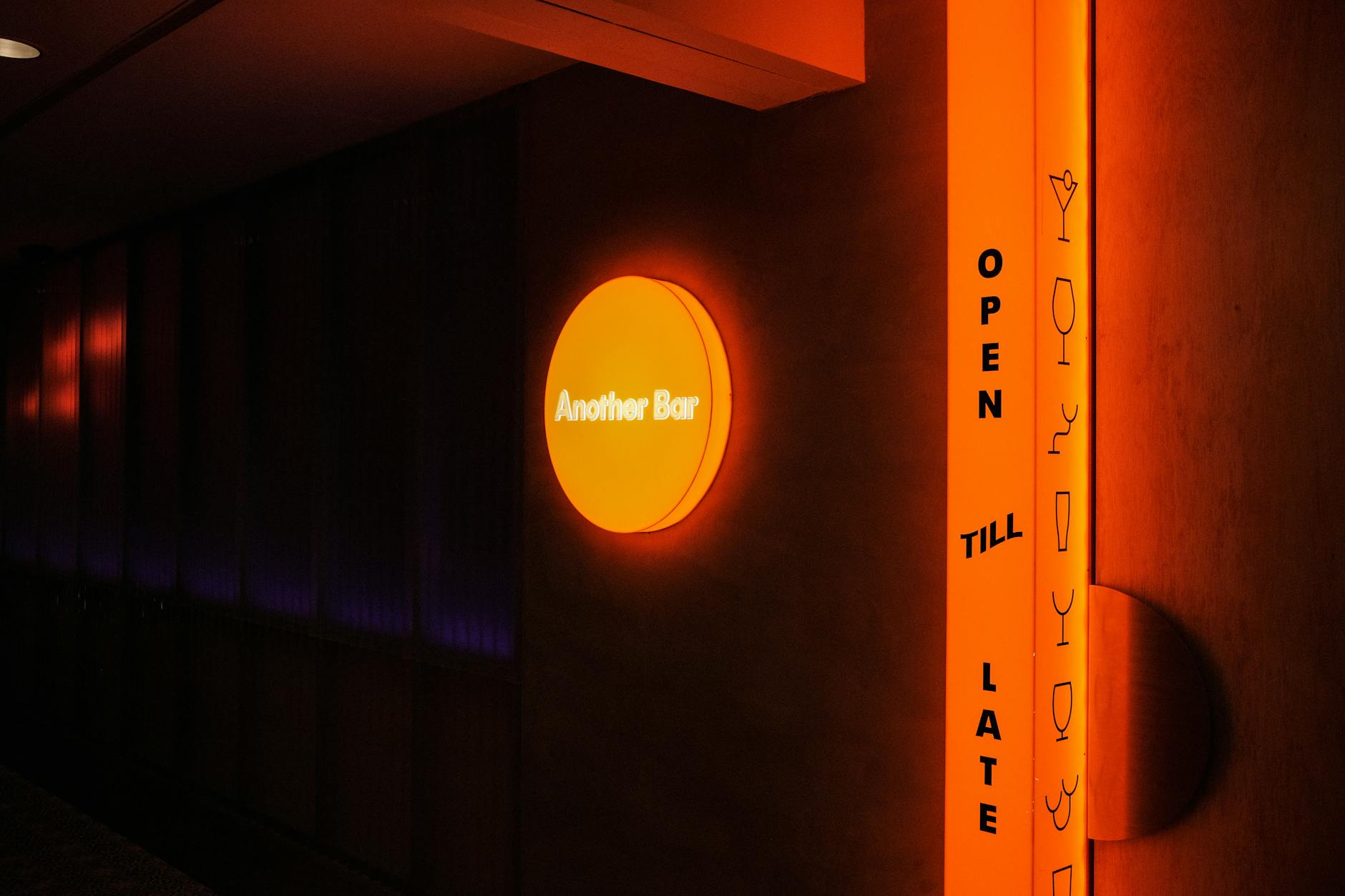 Vibrant neon signage for 'Another Bar' with a stylish design, open till late at night.