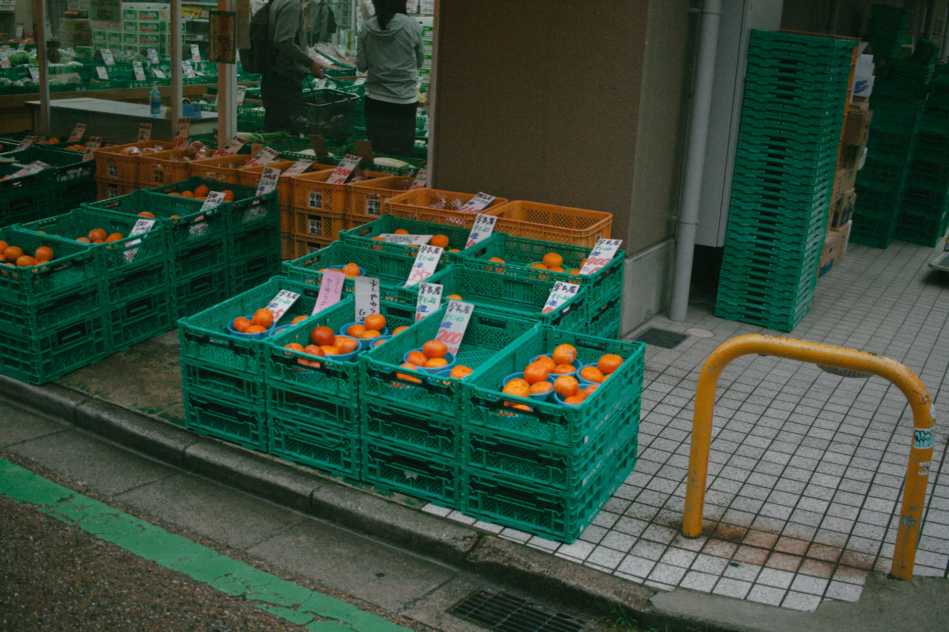 Vibrant street market in Tokyo showcasing fresh oranges in colorful crates.