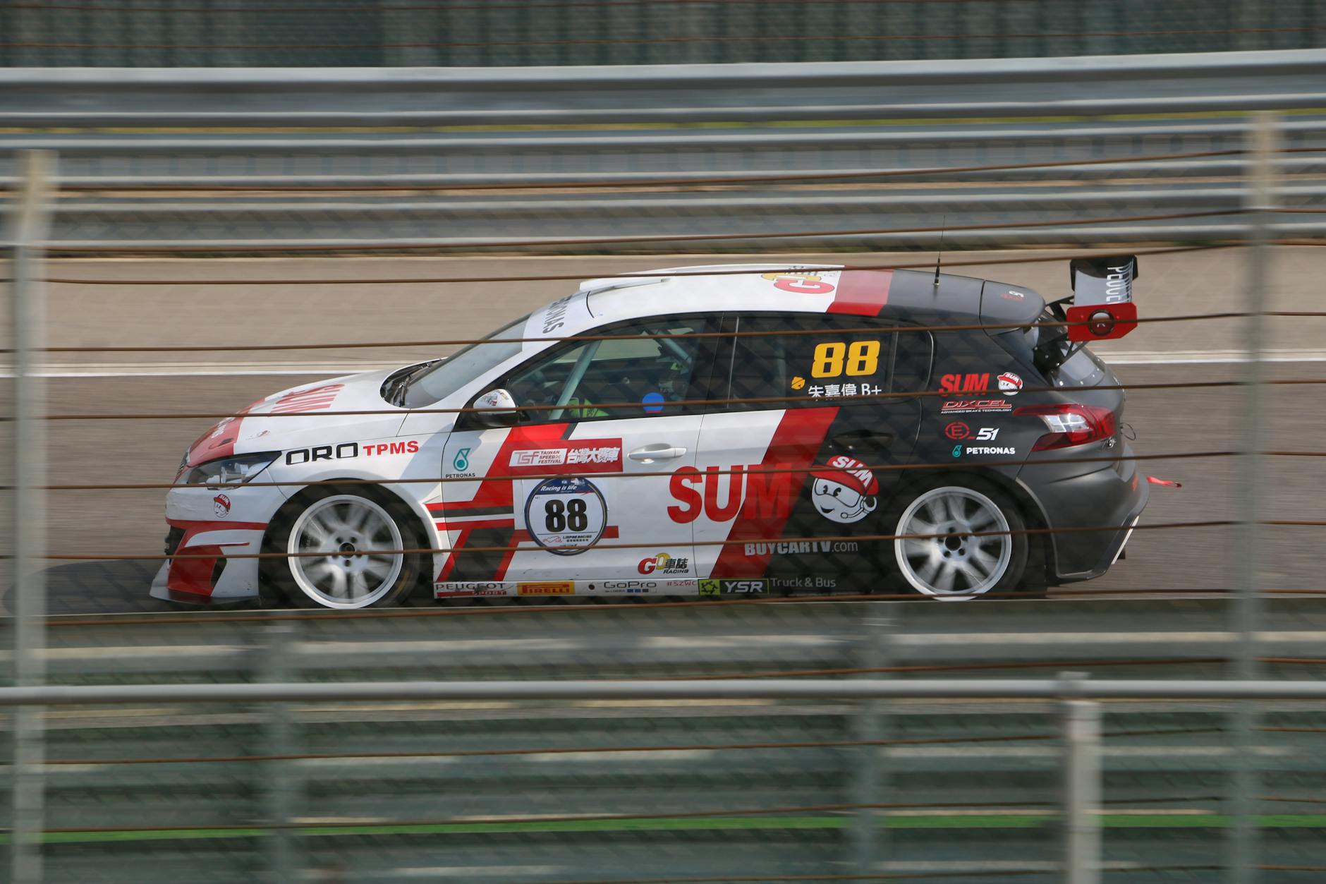 Action shot of a fast race car speeding on a Taiwan racetrack, blurred background conveying speed.