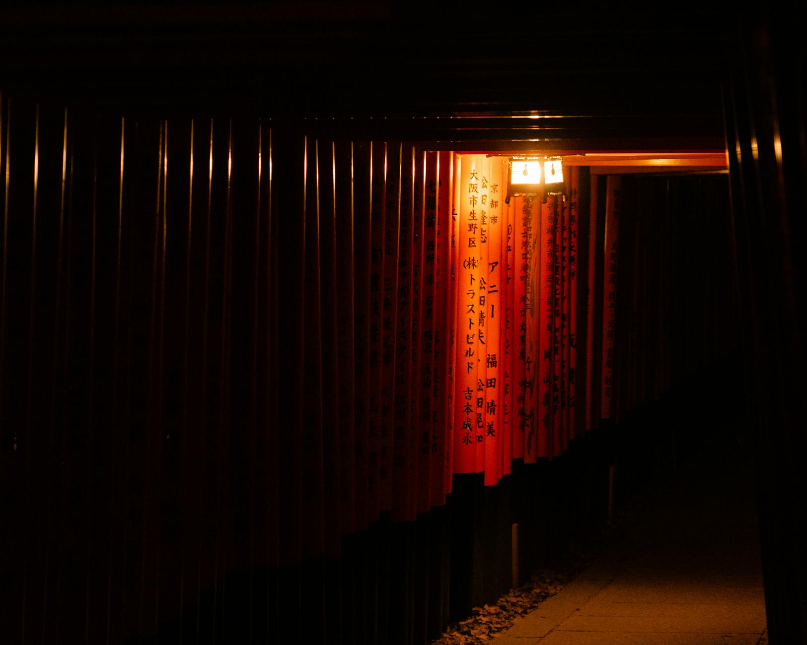 Illuminated torii gates at Fushimi Inari Taisha in Kyoto captured at night, evoking a sense of serenity and ancient tradition.