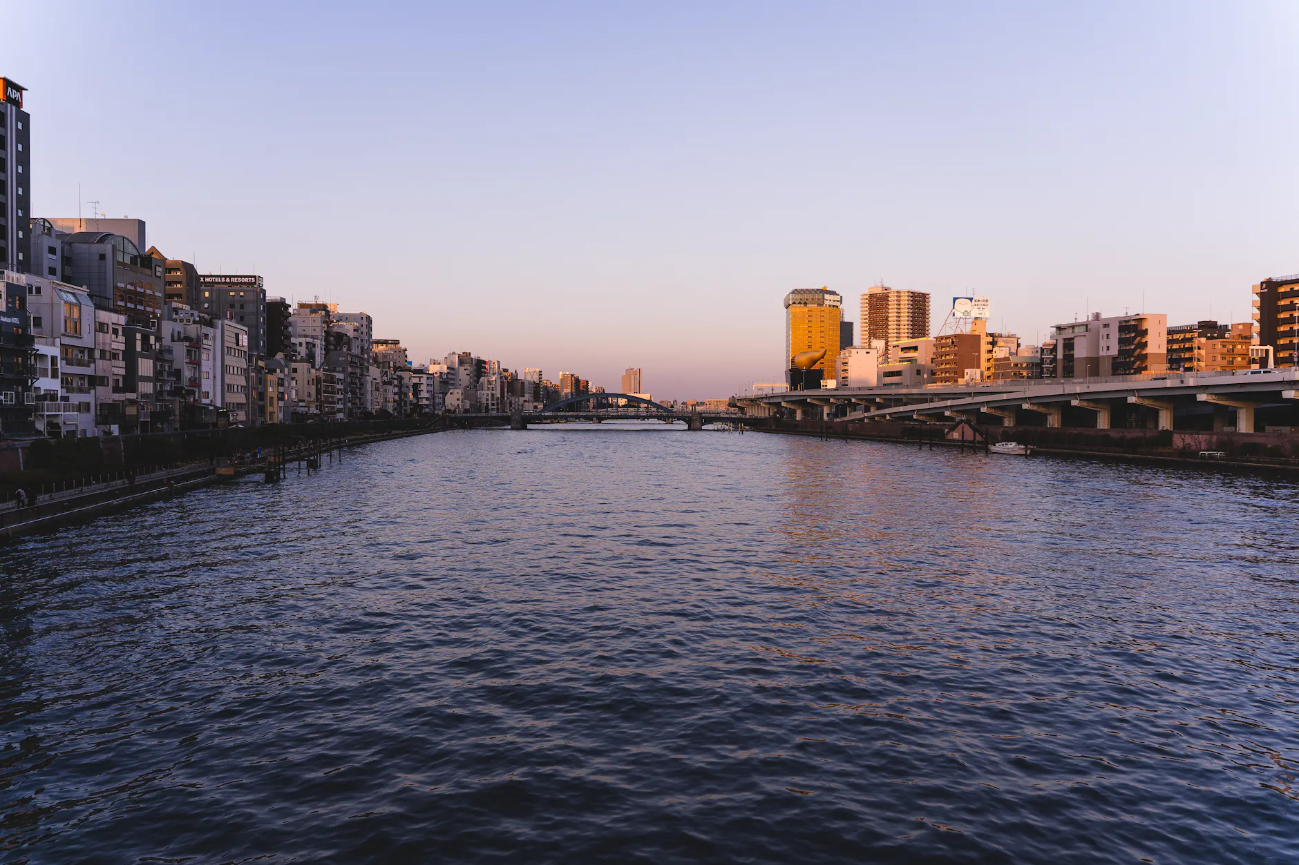 Stunning view of Sumida River in Tokyo, Japan during golden hour with a scenic bridge.