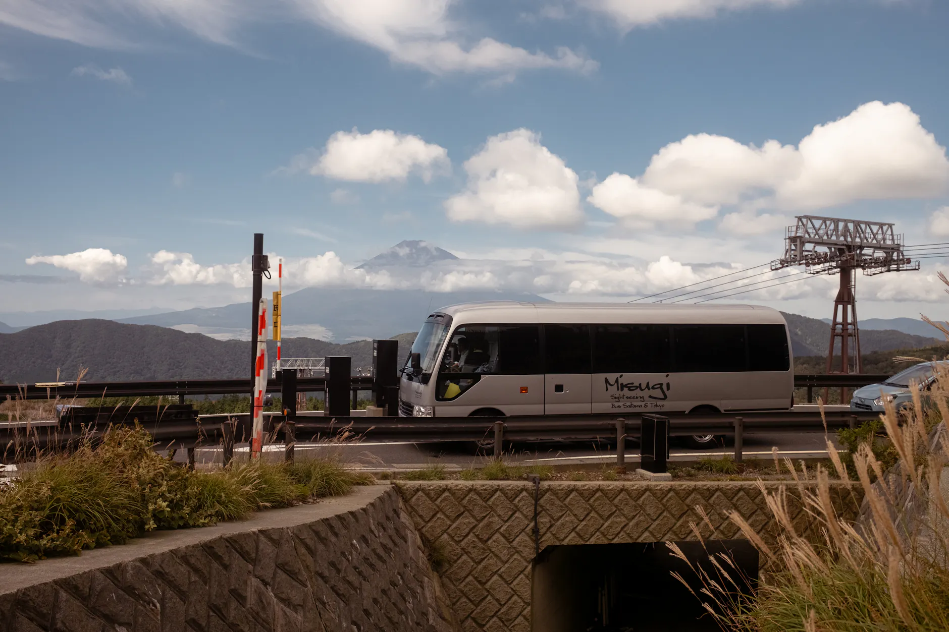 Tourist bus traveling in Hakone with Mount Fuji backdrop on a clear day.
