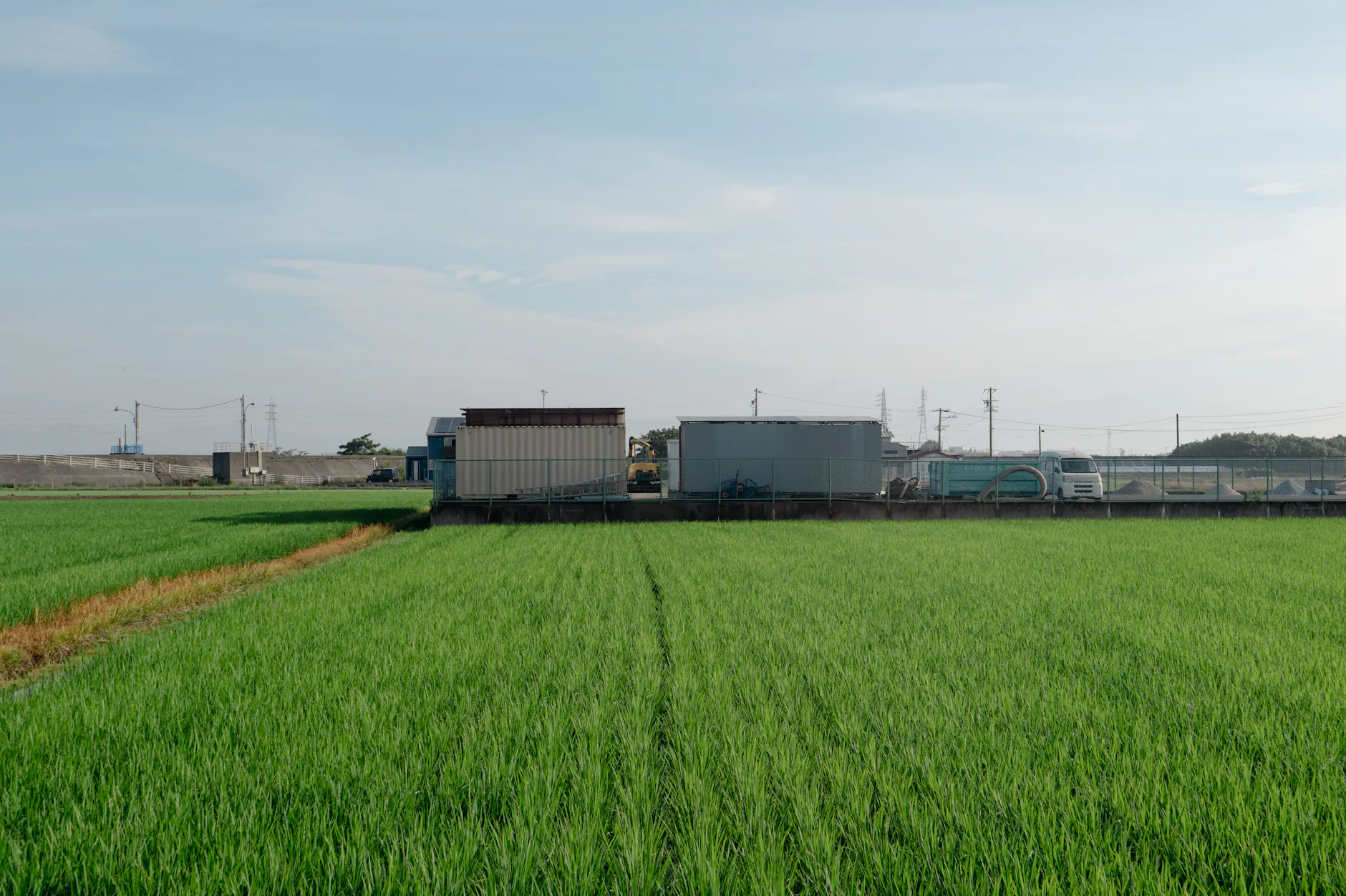 Expansive green field with industrial backdrop in Toyohashi, Aichi, Japan on a sunny day.