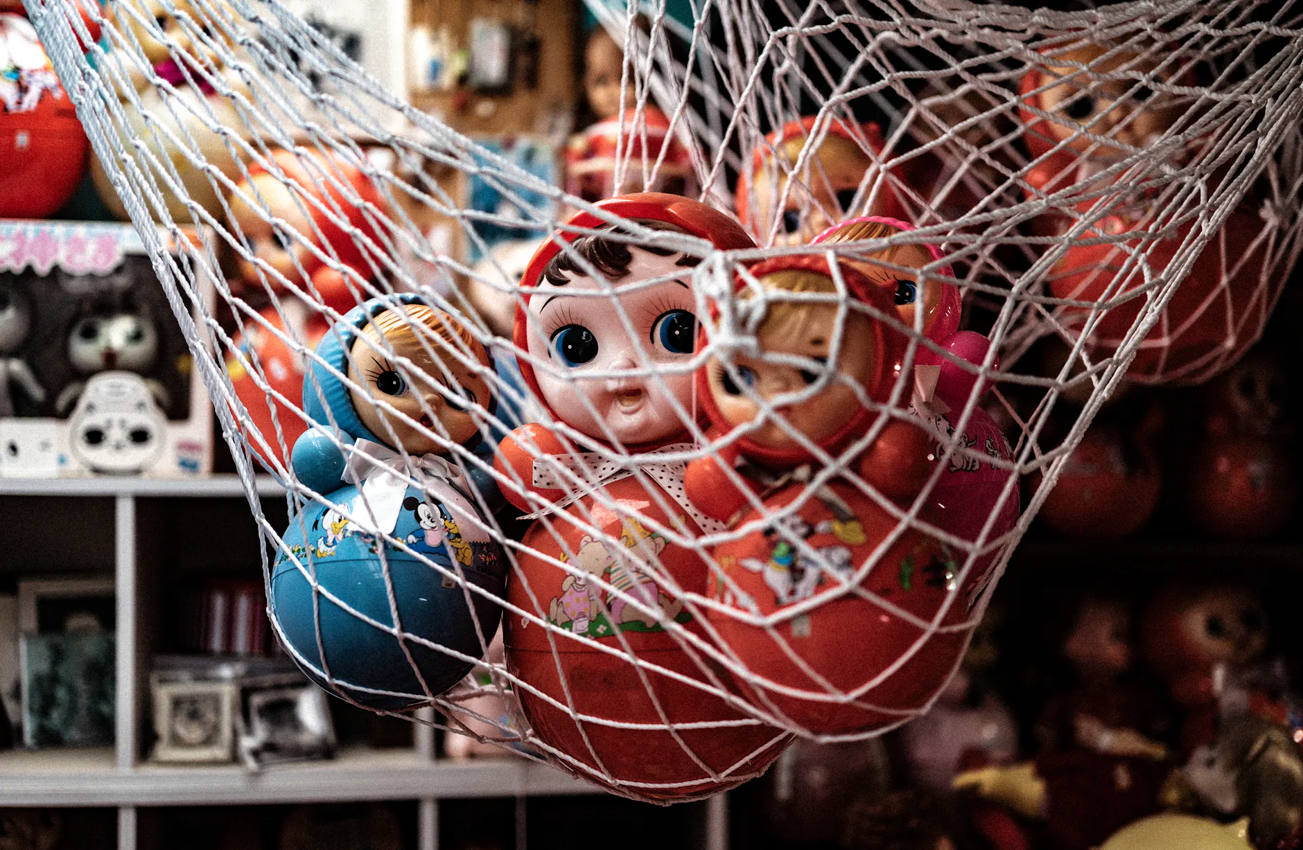 Vibrant collection of vintage dolls in a net display at a museum, capturing a nostalgic Japanese art style.