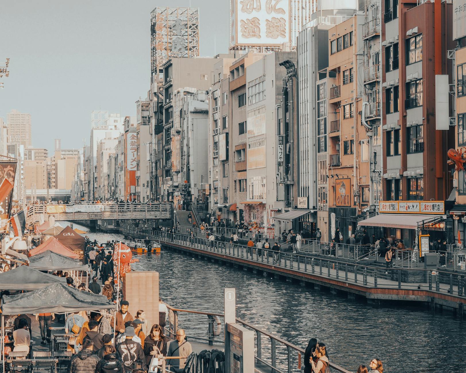 Vibrant cityscape of Kyoto's canal area with pedestrians and colorful buildings showcasing urban life.