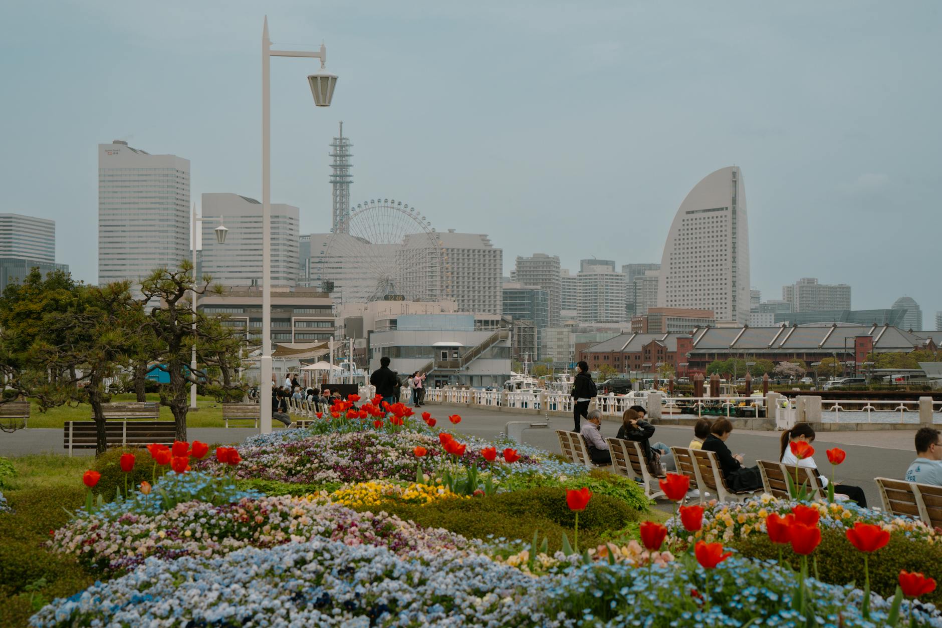 Vibrant spring flowers with Yokohama cityscape, including iconic landmarks, under a bright daytime sky.