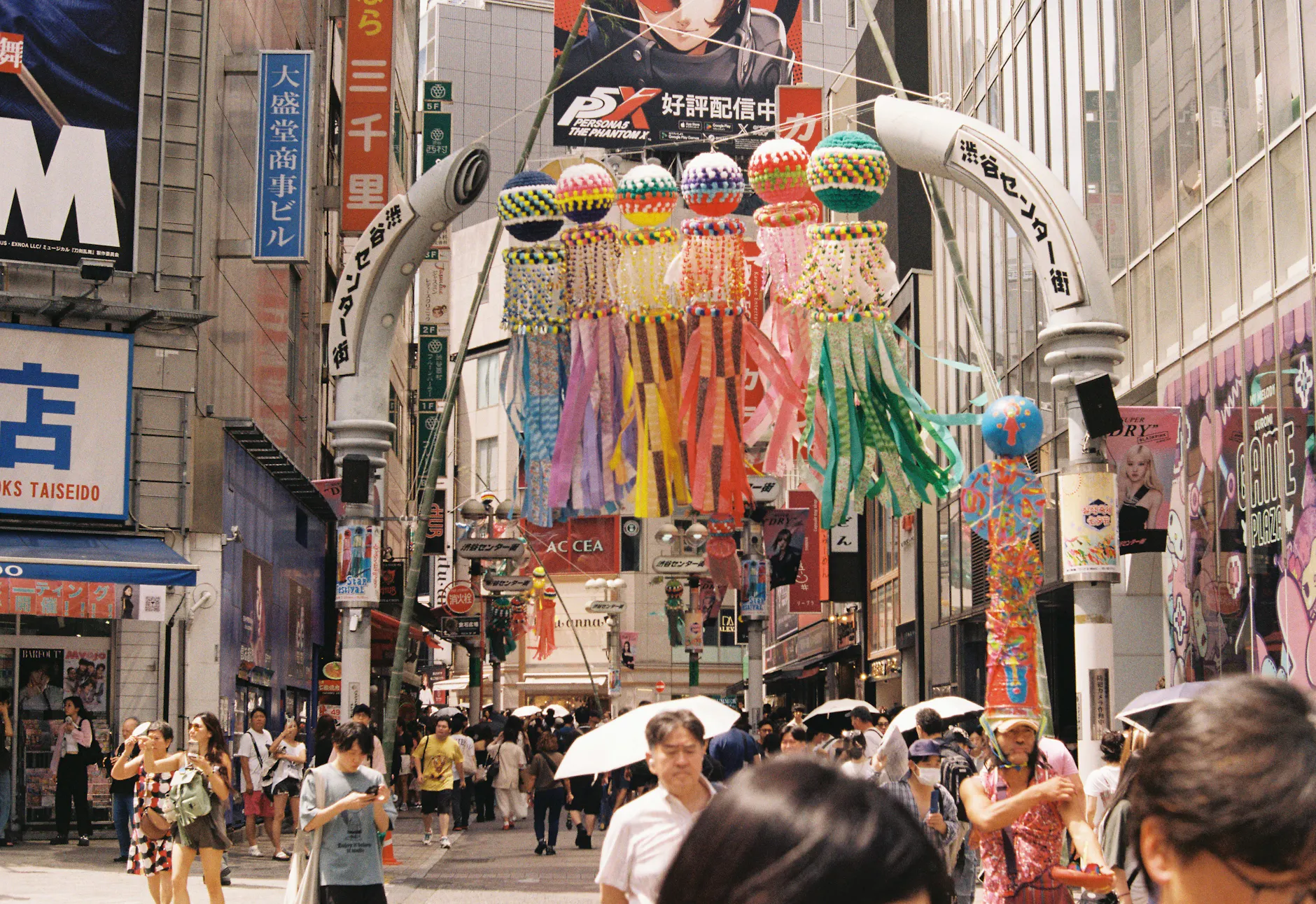 Busy Shibuya street in Tokyo with colorful decorations and bustling crowd.