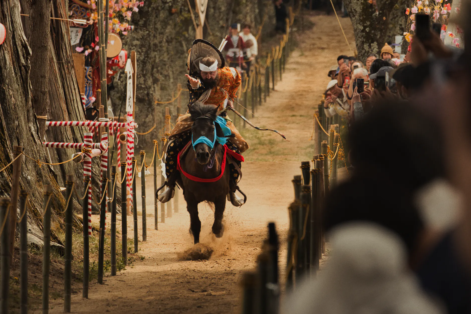 Japanese Yabusame archer on horseback shooting an arrow during a festival.