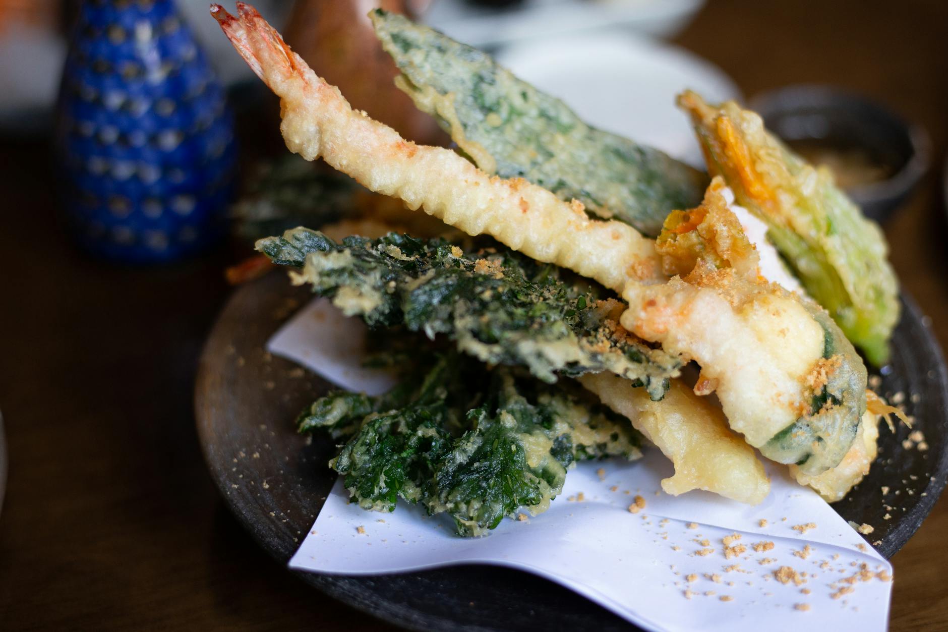Japanese tempura set featuring shrimp and vegetables on a dark plate