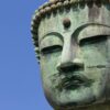 Detailed close-up of the Kamakura Daibutsu Buddha statue under a clear blue sky in Japan.