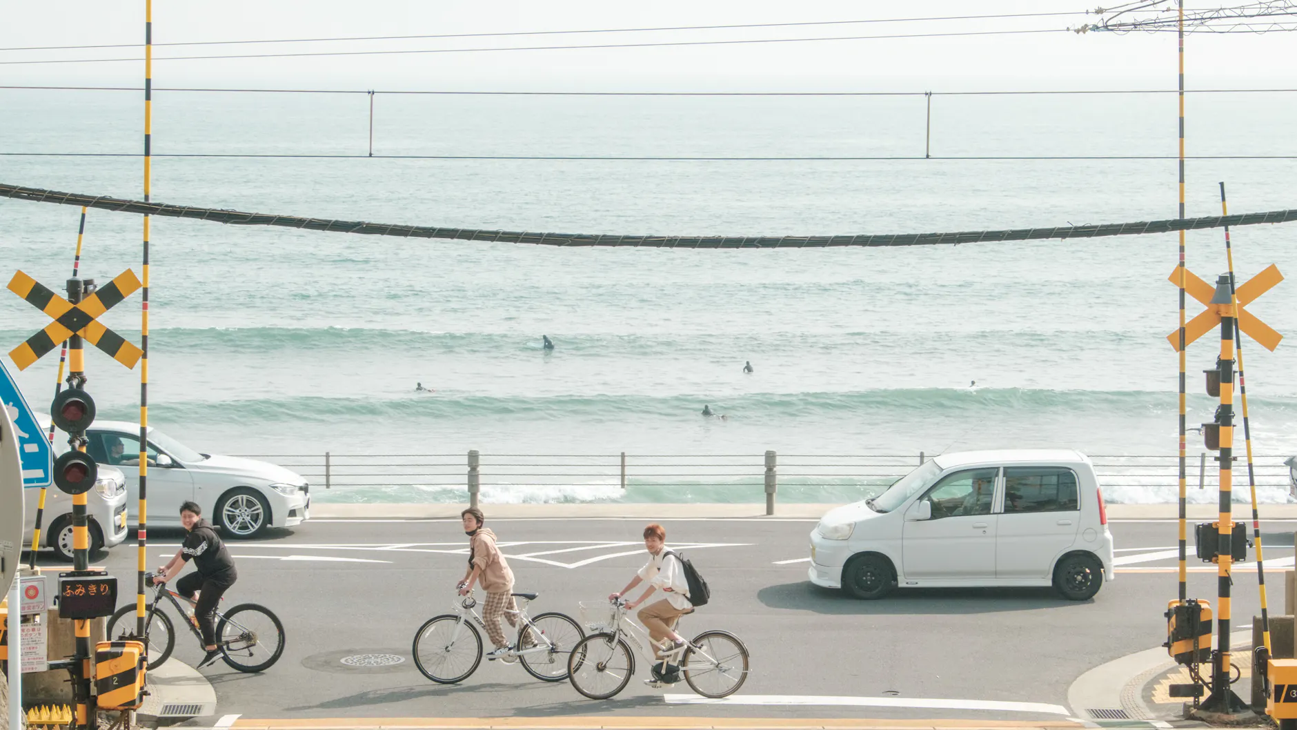Cyclists riding near a coastal road with a scenic ocean view and vehicles passing by.