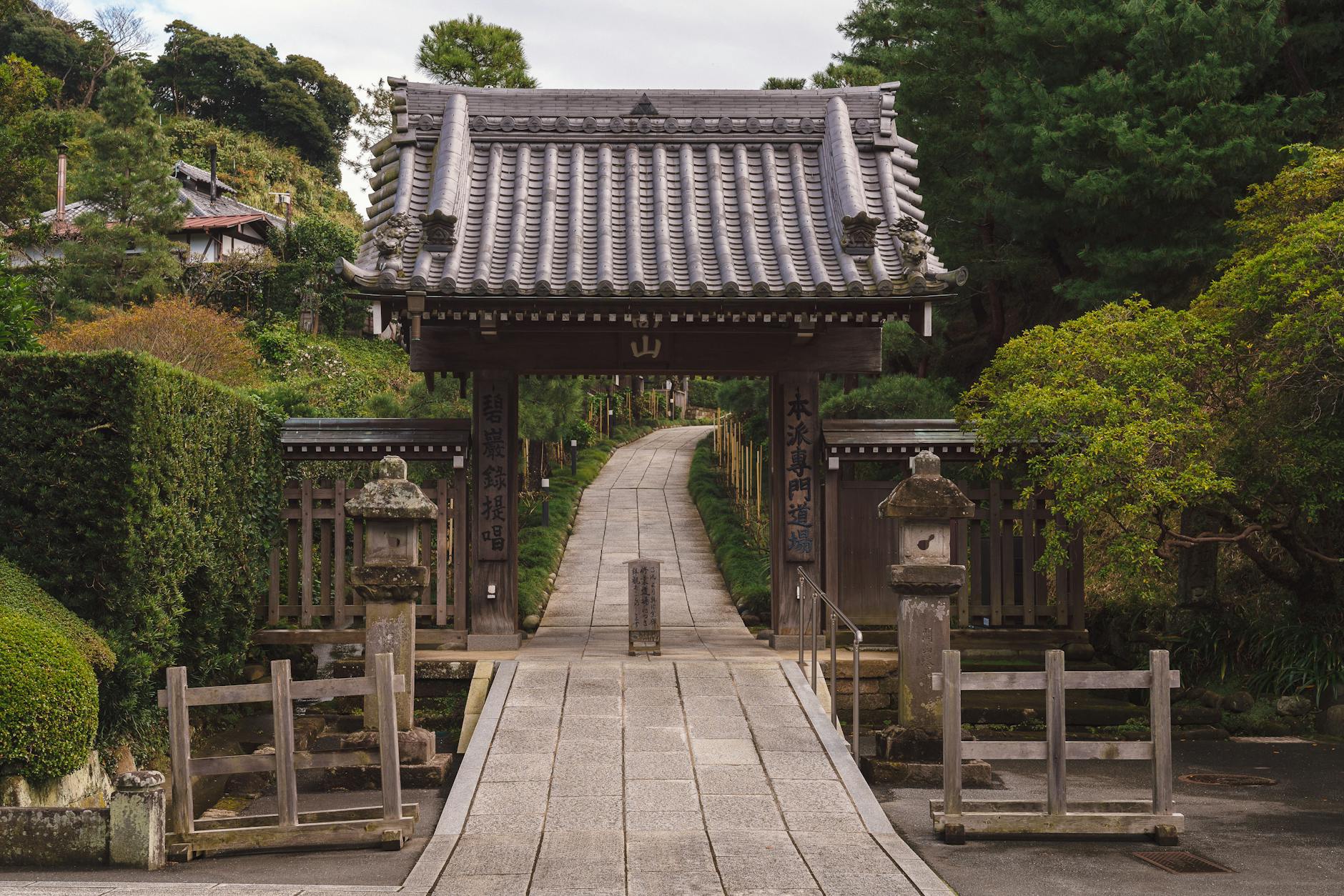 Explore the serene pathway leading to a traditional Japanese gate at Kencho-Ji Temple in Kamakura.