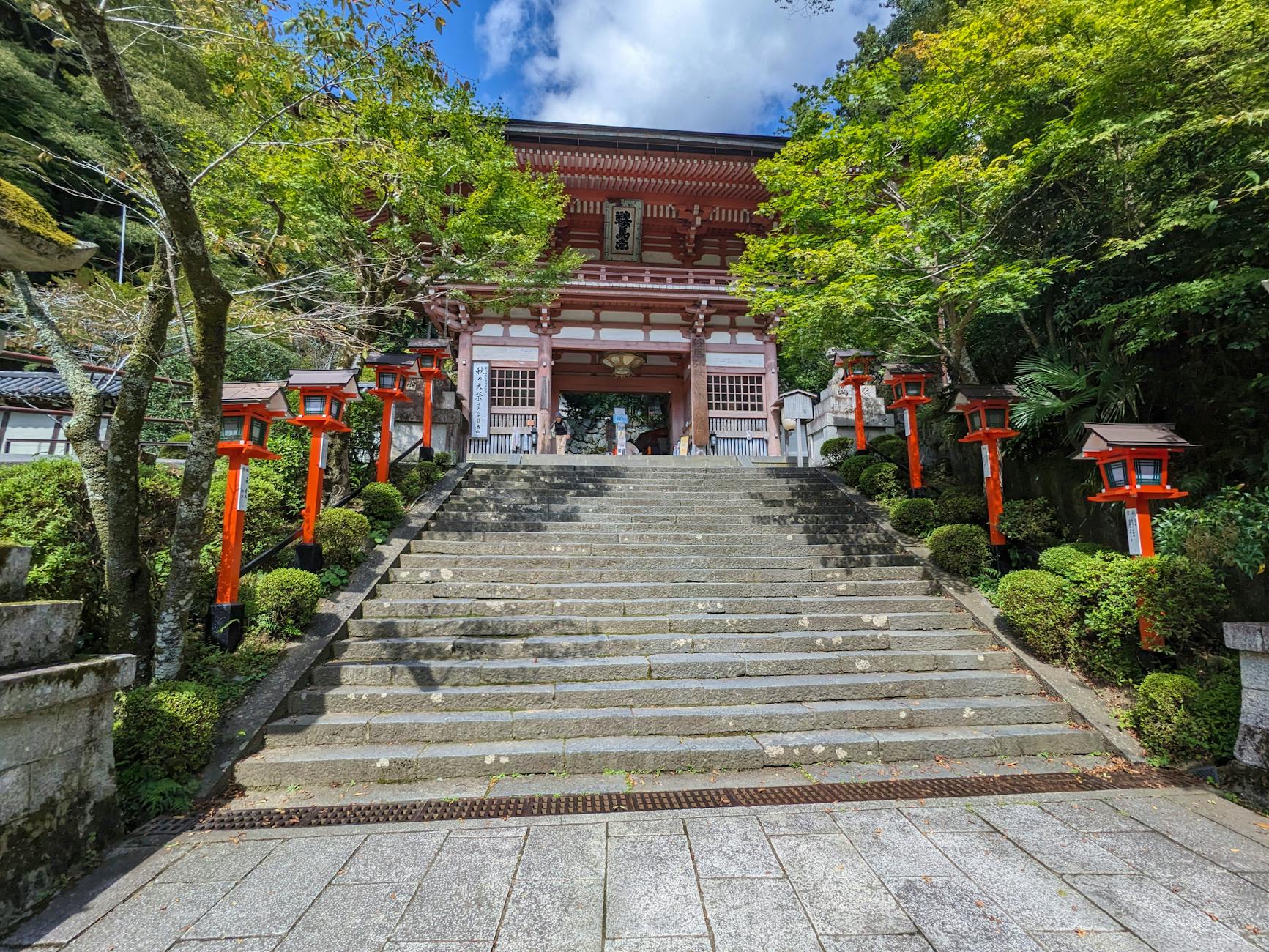 Beautiful stairs leading to Kurama Temple in Kyoto, framed by lush greenery and traditional red lanterns.