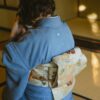 Back view of unrecognizable person wearing authentic robe sitting on tatami while drinking tea from bowl during traditional Japanese ceremony
