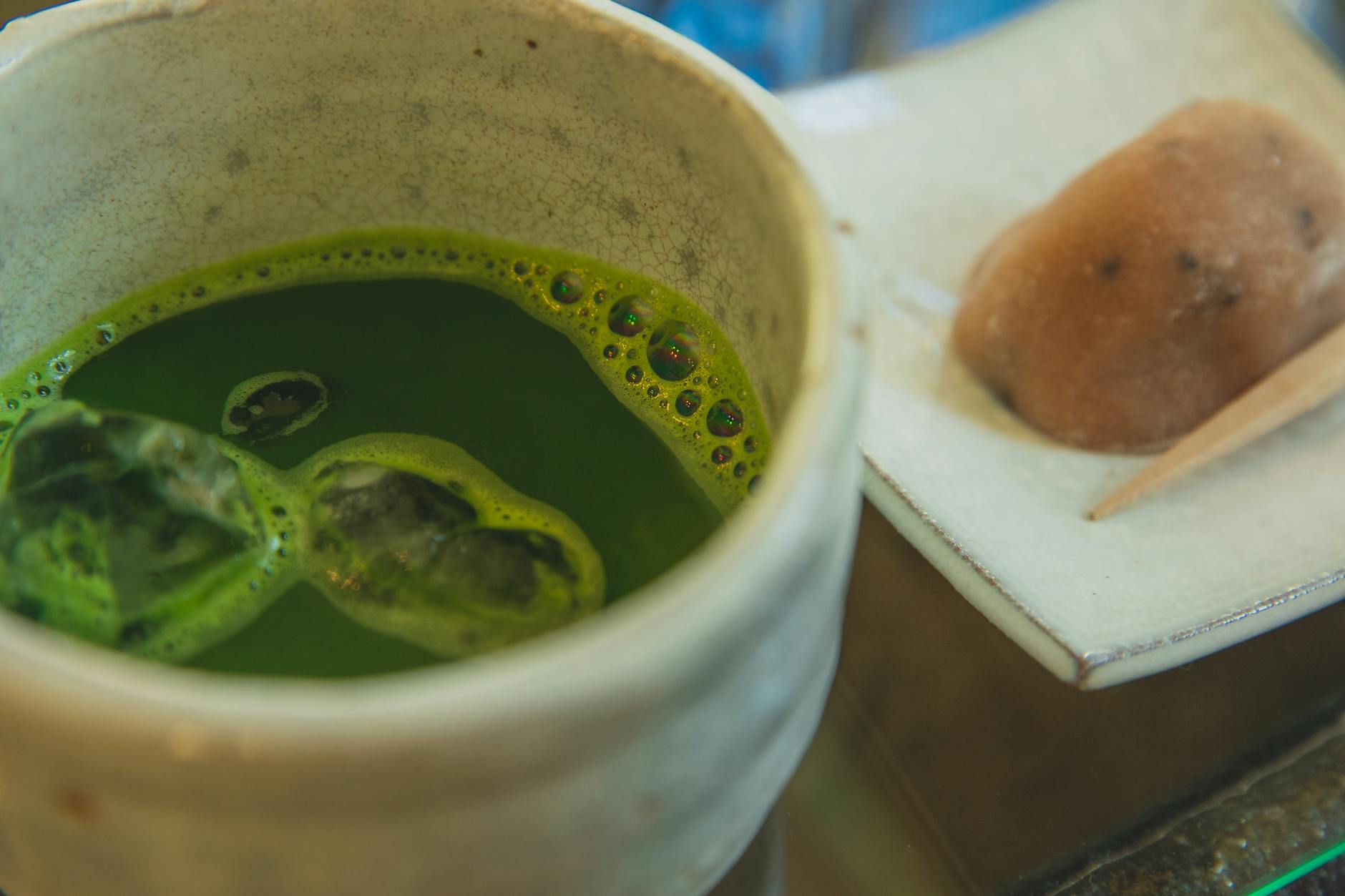 Cup of green matcha tea with ice and traditional wagashi sweets