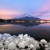 Captivating sunset over Mount Fuji reflected in a serene lake with icy foreground.