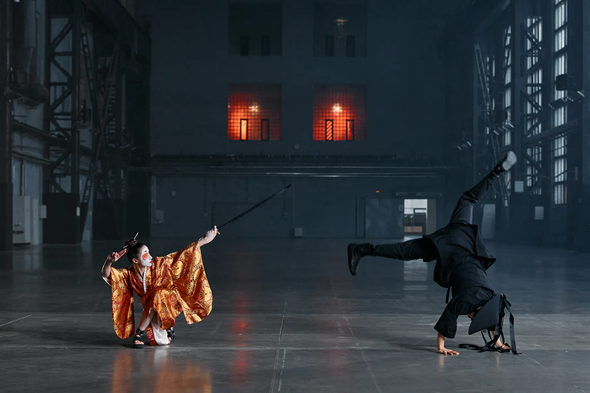 A martial arts duel with costumes and swords in a vast industrial warehouse.