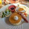 A scrumptious breakfast featuring pancakes, fried egg, sausage, and salad, perfect for a morning meal.