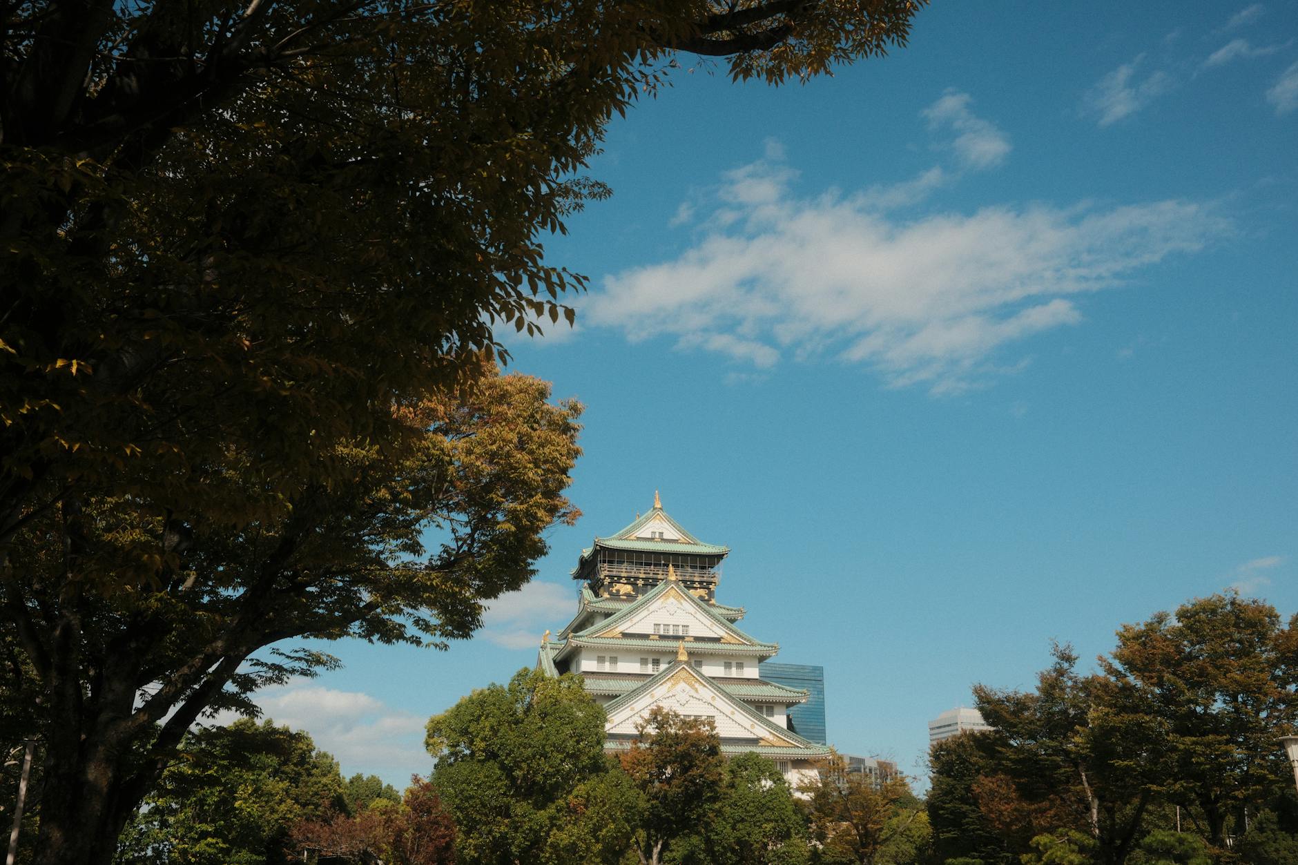 Scenic view of Osaka Castle surrounded by trees under a clear blue sky.
