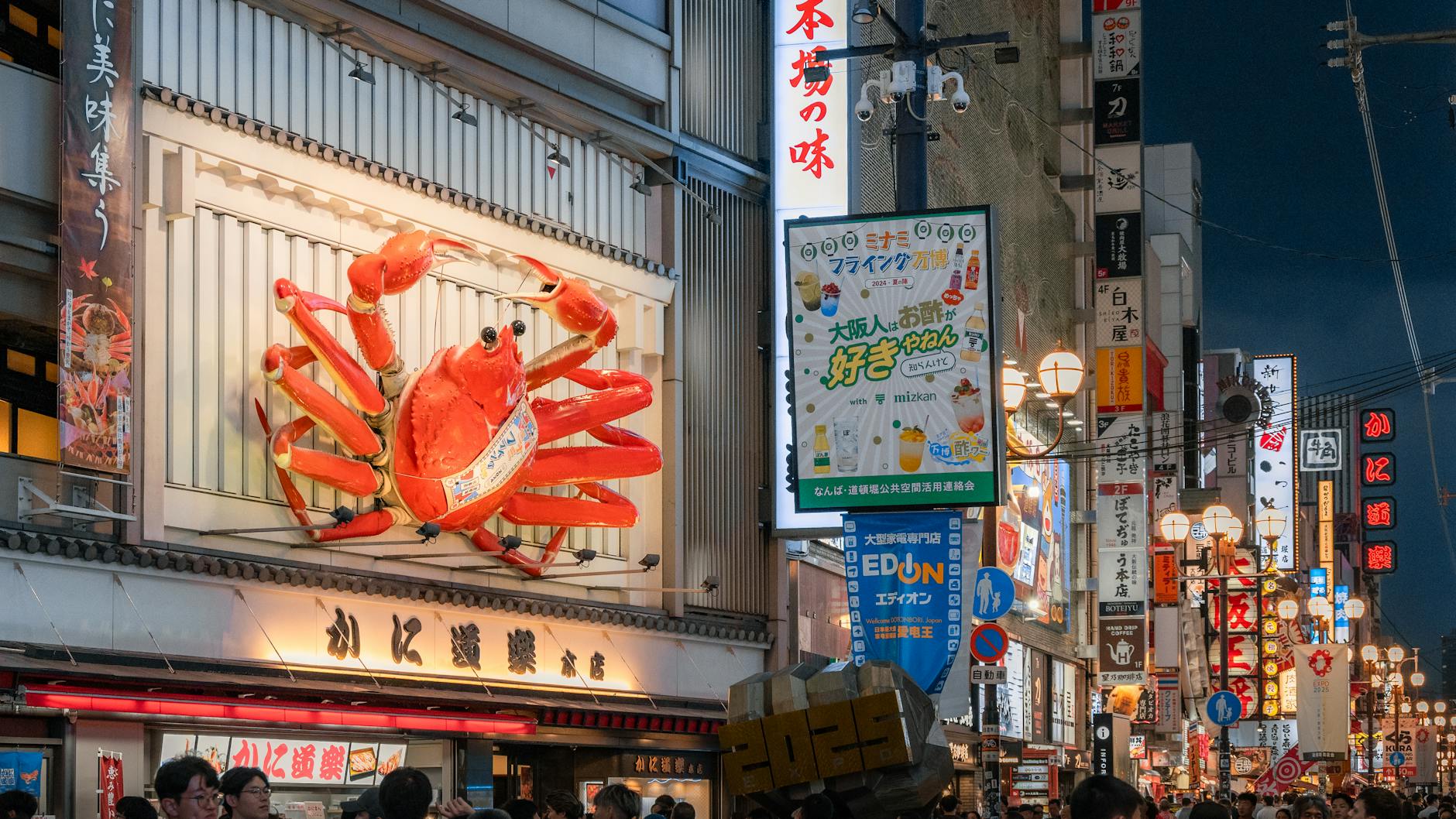 Vibrant night scene of Osaka street featuring large crab sign and bustling crowds.