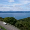 Aerial view of a car on a road overlooking Hakodate's coastline and sea in Hokkaido, Japan.