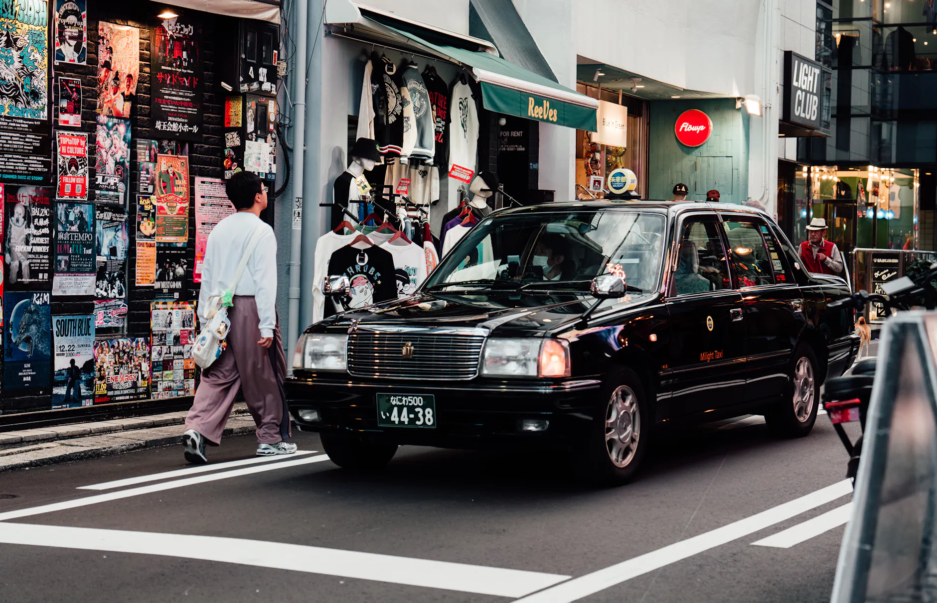 Vibrant street scene in downtown Osaka featuring a taxi and diverse storefronts.