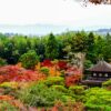 Scenic view of a Kyoto temple surrounded by vibrant autumn foliage and lush greenery.