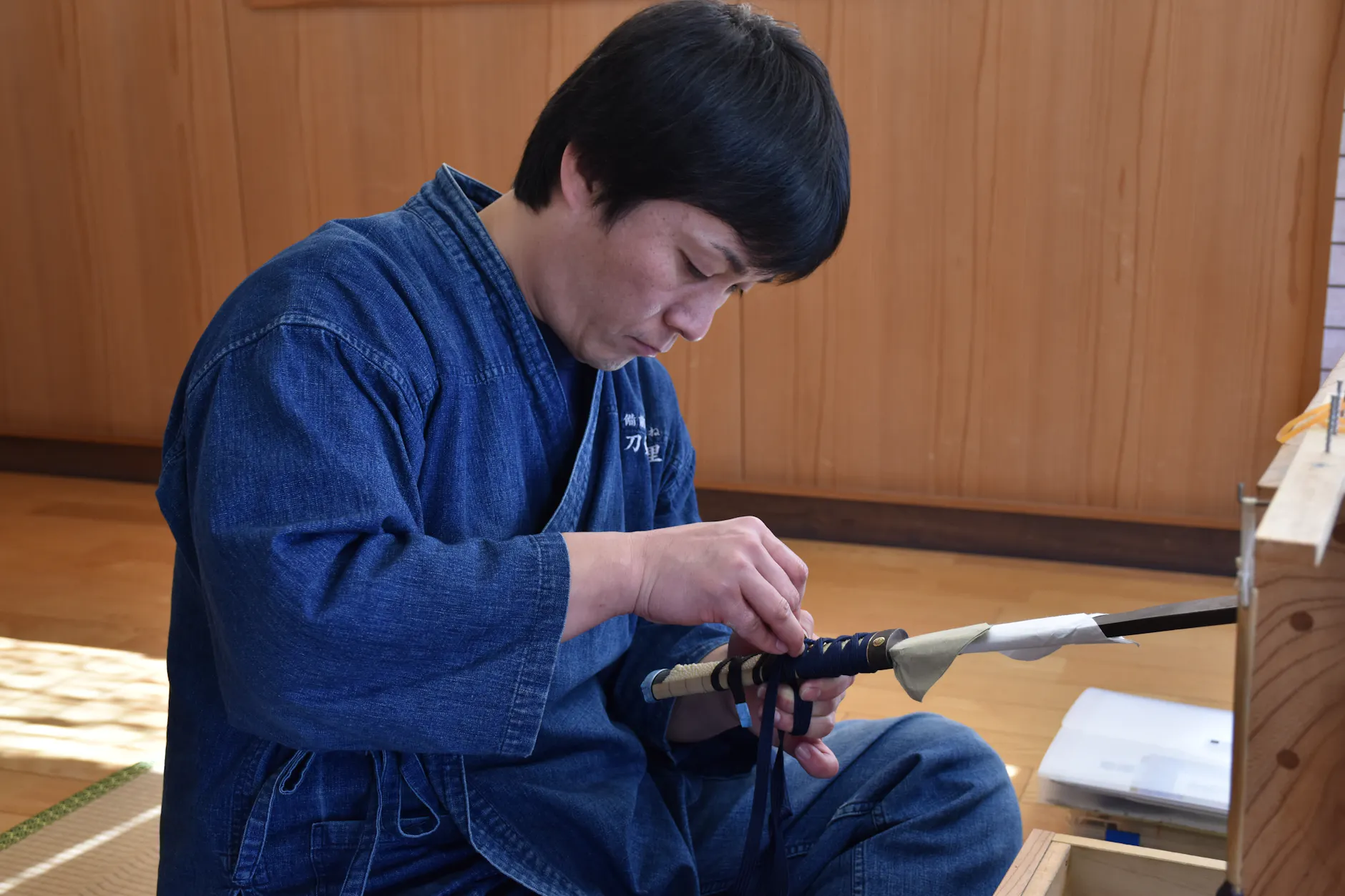 Skilled Japanese craftsman attentively crafting a traditional katana sword indoors, showcasing delicate artistry.
