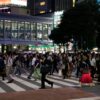 Pedestrians cross Shibuya Crossing, Tokyo at night, showcasing urban vibrancy.