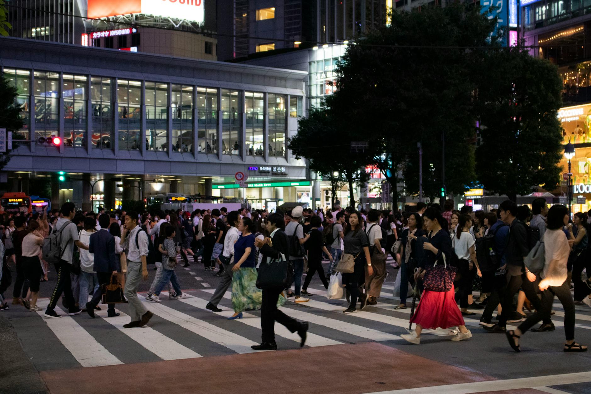 Pedestrians cross Shibuya Crossing, Tokyo at night, showcasing urban vibrancy.