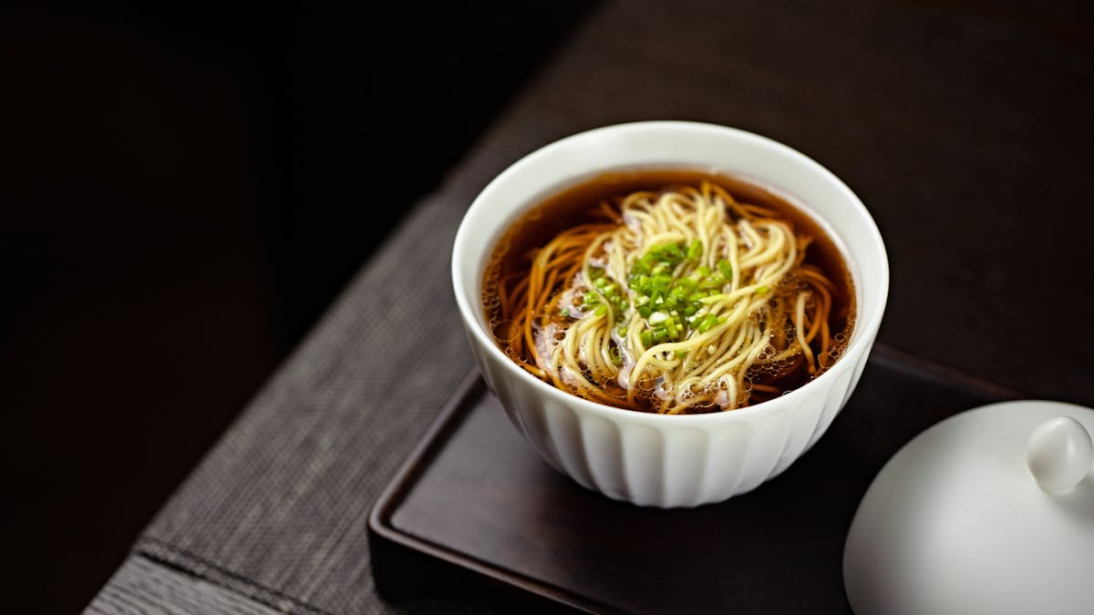 Authentic soba noodles in savory dashi broth garnished with green onions - traditional Japanese soba restaurant Tokyo