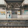 A woman walking along a train platform at a Tokyo station, showcasing the station's architecture and mood.
