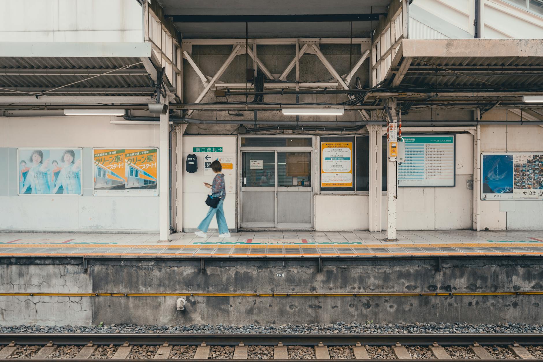 A woman walking along a train platform at a Tokyo station, showcasing the station's architecture and mood.