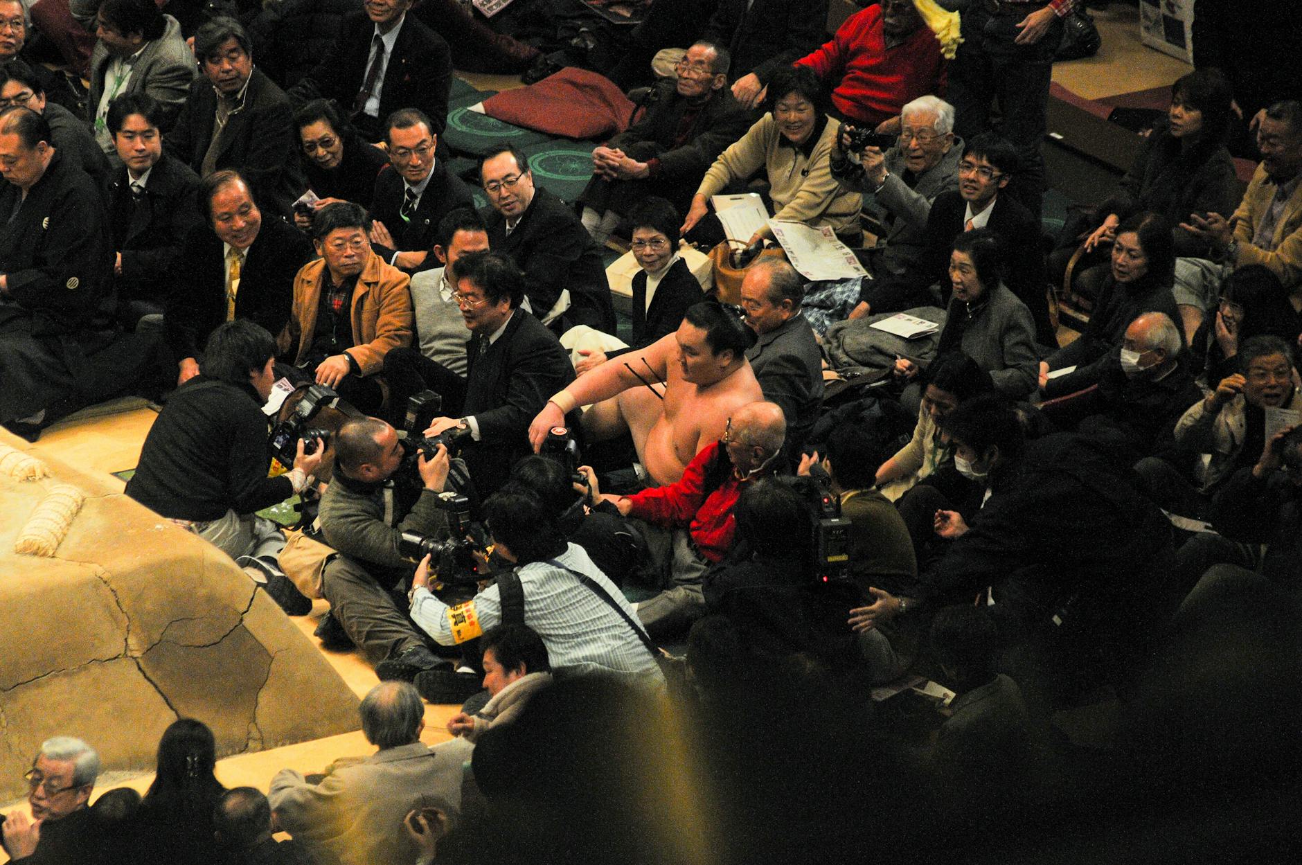 Sumo wrestling event with photographers capturing the scene, vibrant cultural moment.