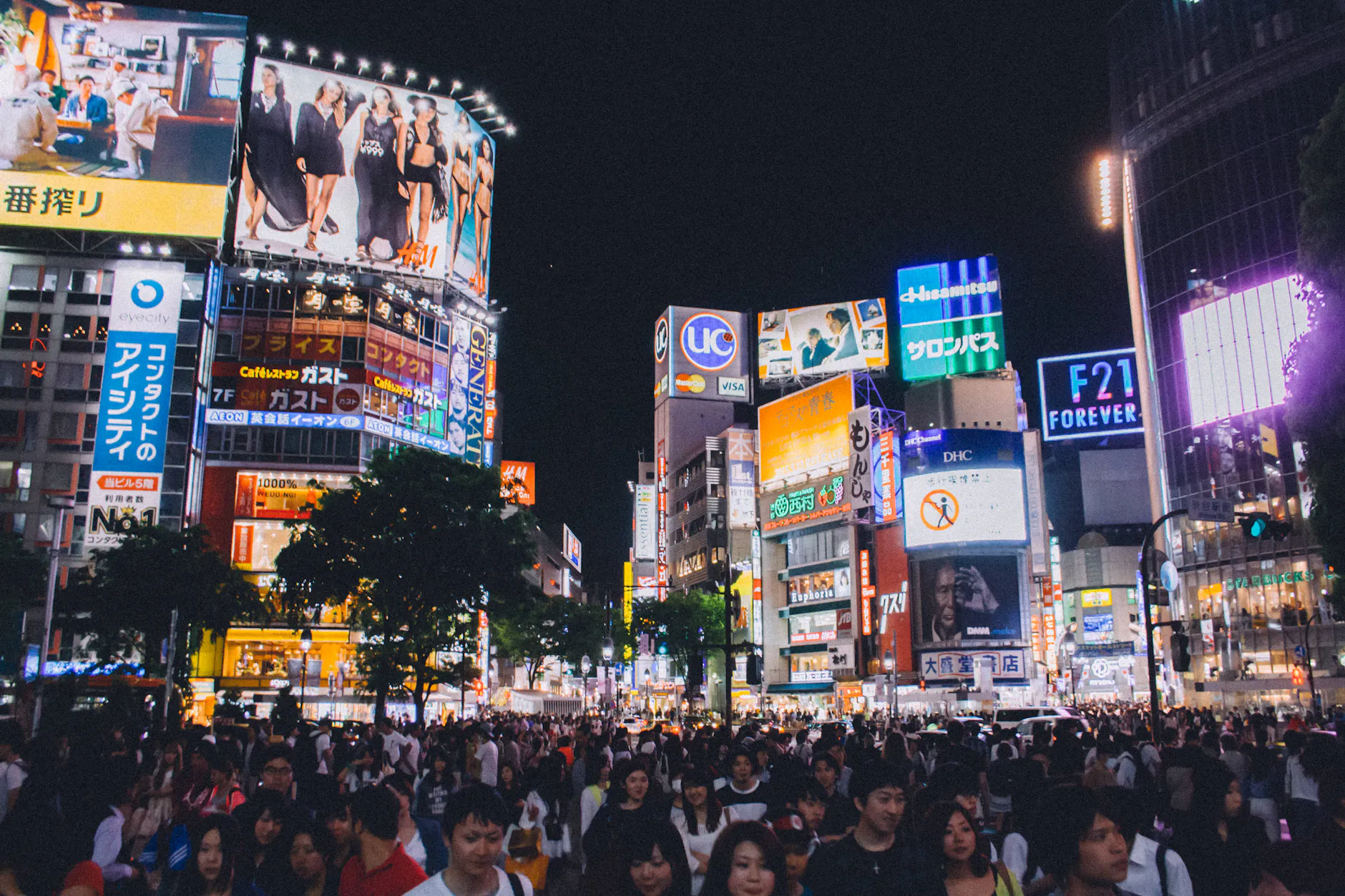 A bustling crowd at Shibuya Crossing under the bright lights of Tokyo's urban night scene.