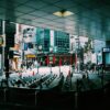 Busy Tokyo street with pedestrians, shops, and bicycles under an urban canopy.