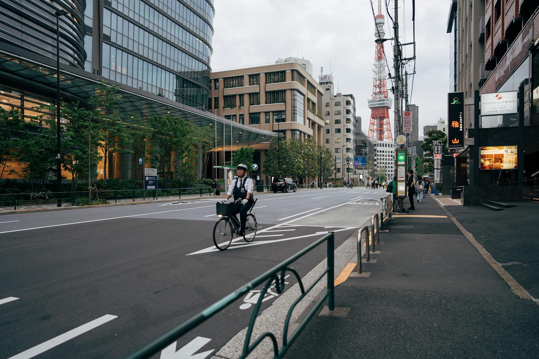 Bicyclist in Tokyo cityscape with Tokyo Tower, modern architecture, and street life.