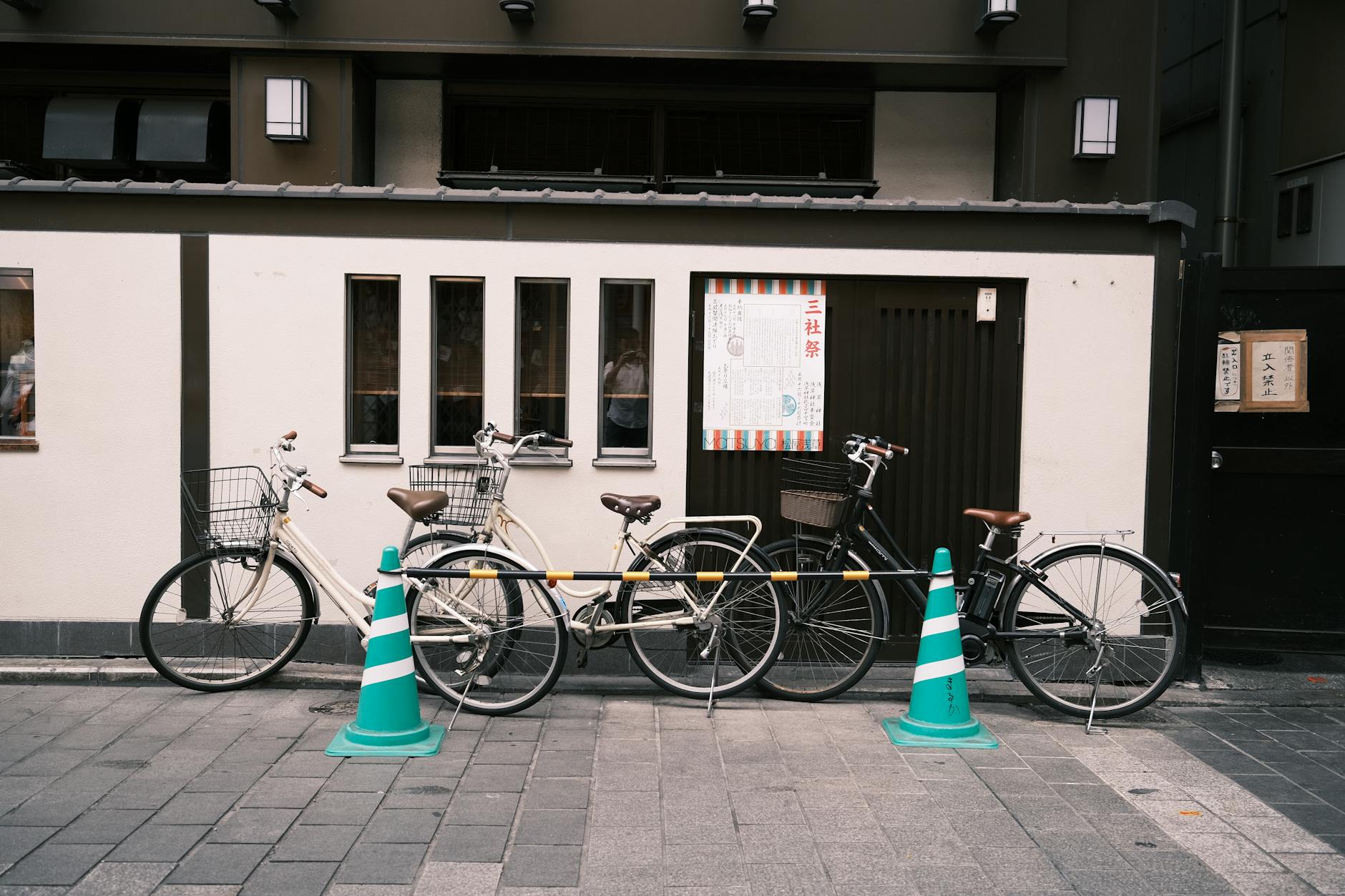 A row of bicycles parked in an urban Tokyo street, framed by modern architecture.