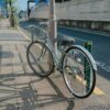 A bicycle with a basket parked on a sunlit sidewalk in Tokyo, Japan.