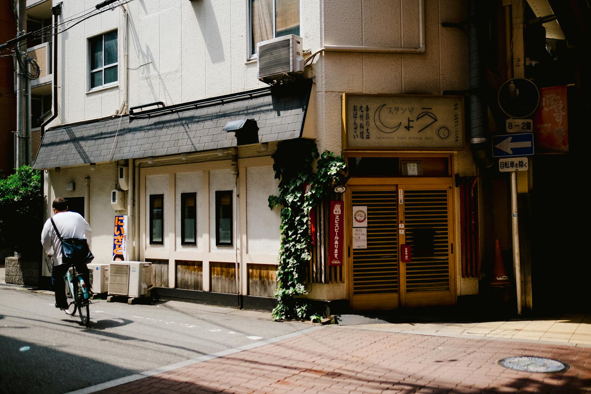 A cyclist passes through a sunlit urban alleyway in the city, showcasing everyday life.
