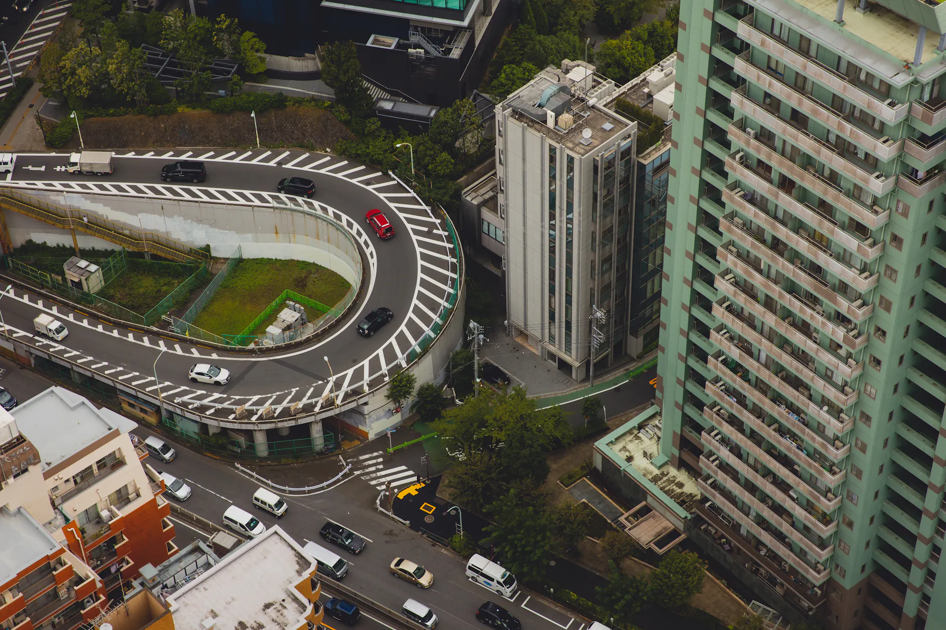From above of modern city with tall buildings and cars rushing on asphalt roads
