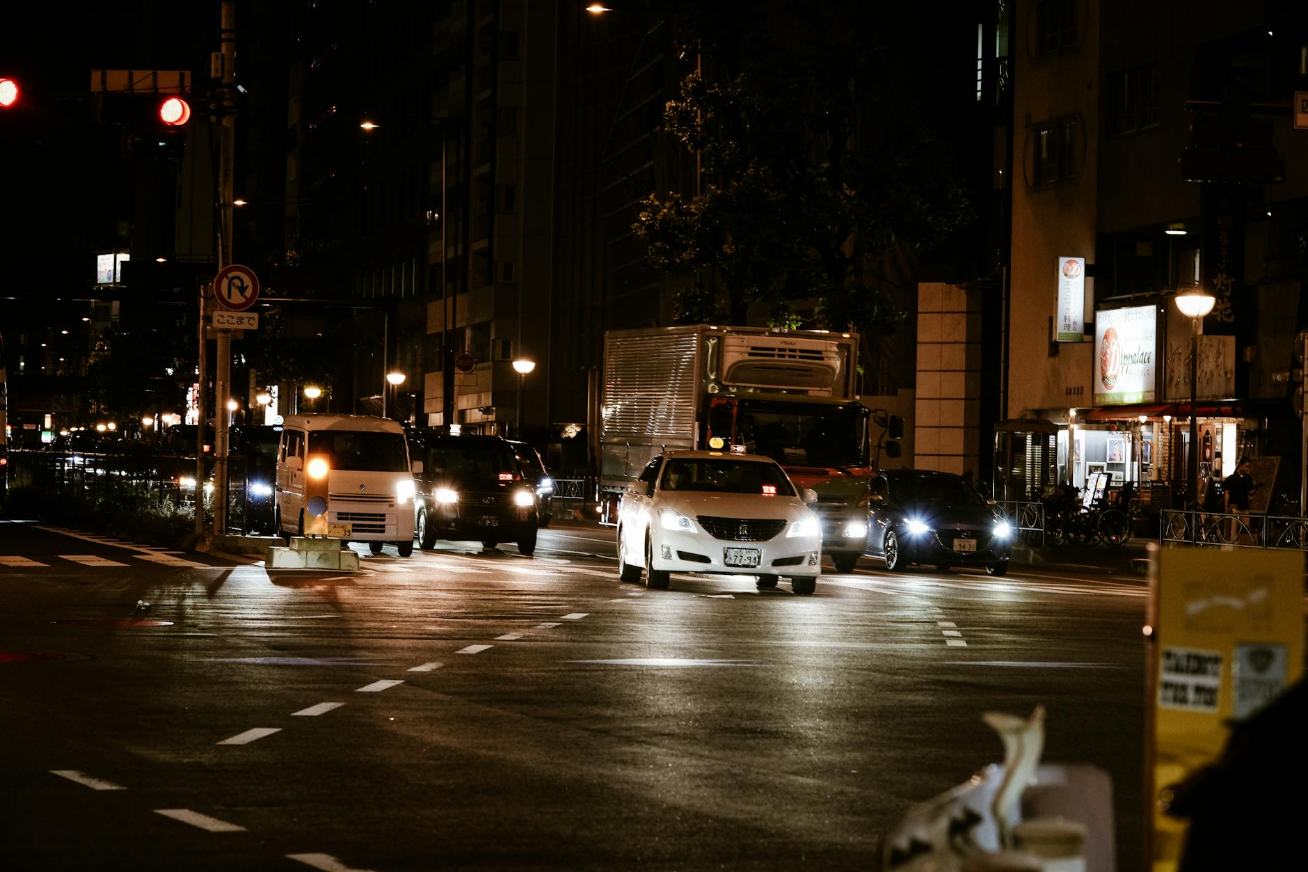 Busy night traffic scene in Shinjuku, Tokyo capturing cars and a vibrant city atmosphere.