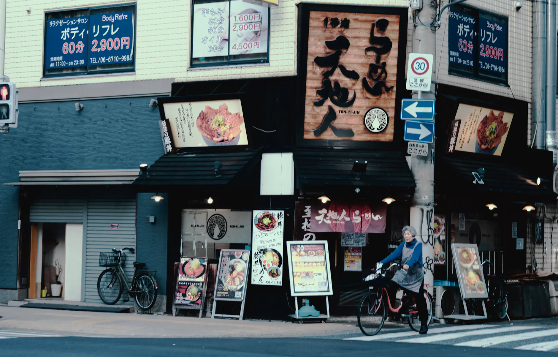 Japanese restaurant storefront with a cyclist in urban setting.