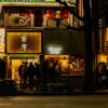 A bustling street in Tokyo with illuminated ramen shops and patrons at night.