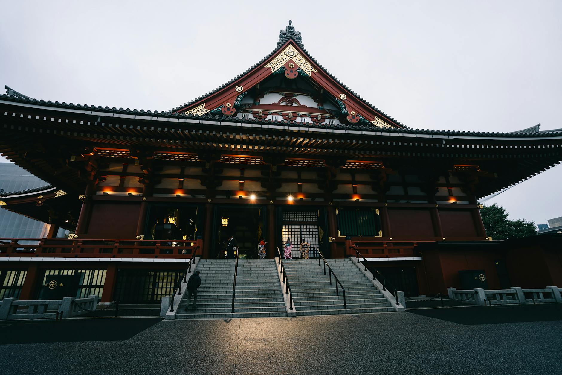 Illuminated historic Japanese temple with grand stairs and intricate architecture.