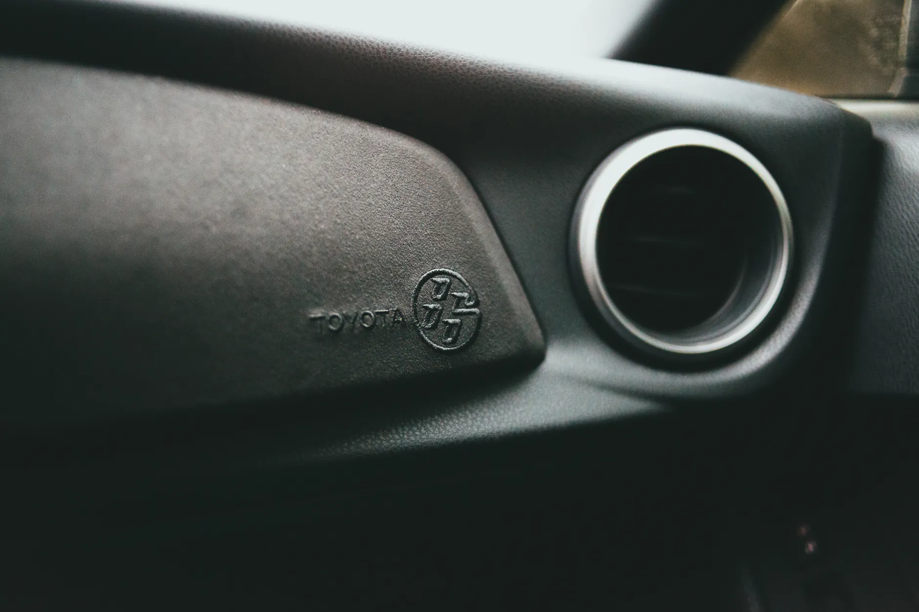 Detail of a Toyota car interior showing steering wheel emblem and air conditioning vent.