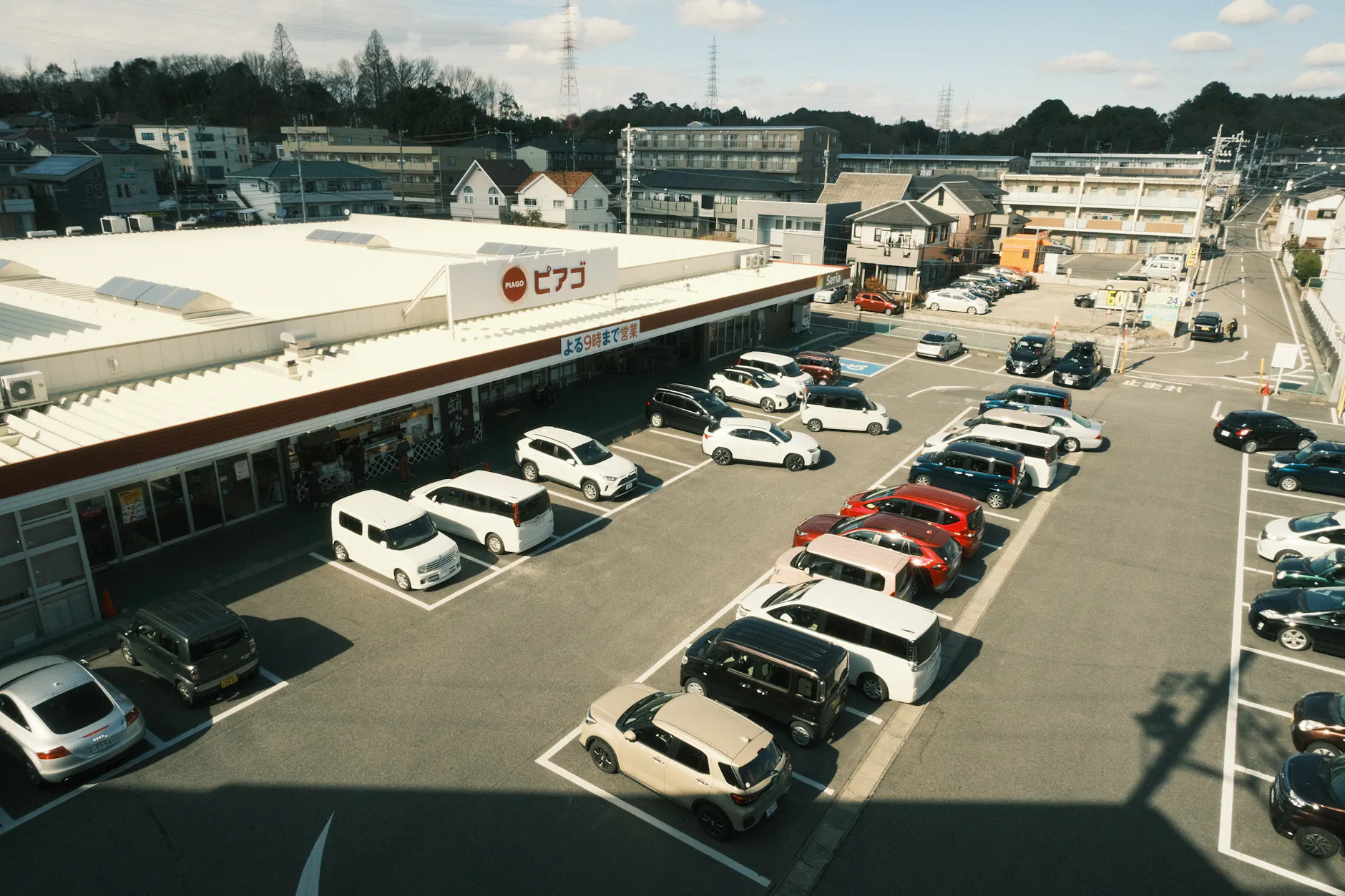 Aerial shot of a supermarket parking lot with parked vehicles in Toyota, Aichi, Japan.