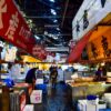 A vibrant scene of vendors and shoppers at Tsukiji fish market in Tokyo during nighttime.