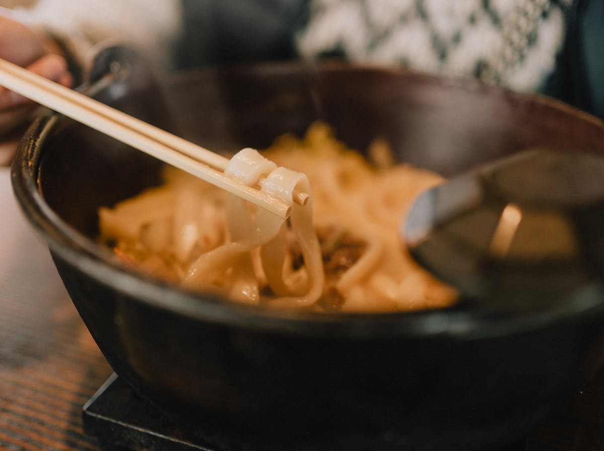 Warm Japanese udon noodle soup in bowl with chopsticks - thick wheat noodles traditional Japanese cuisine