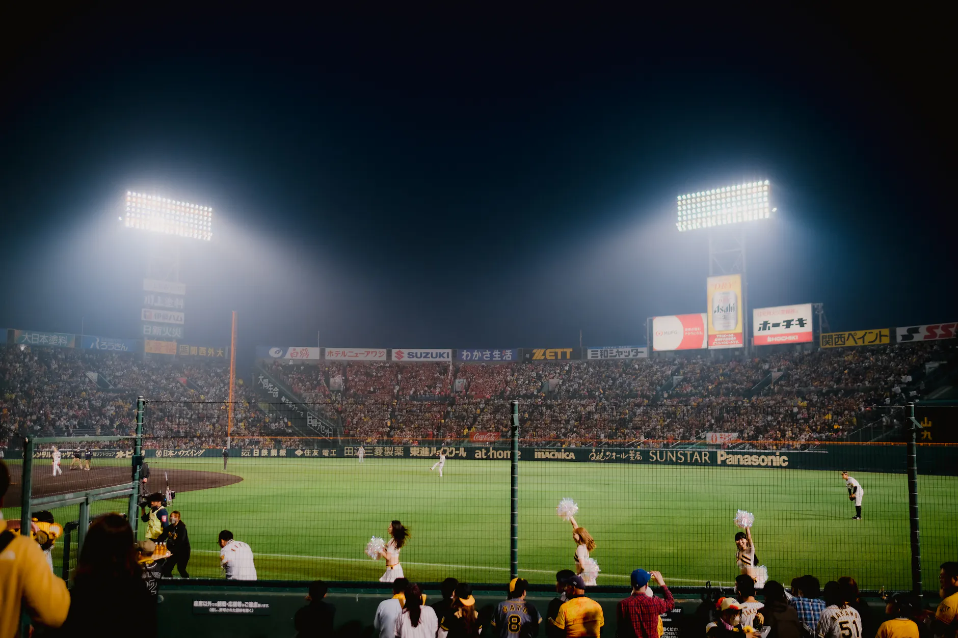 Thrilling night baseball game at Hanshin Koshien Stadium in Japan with vibrant crowd.